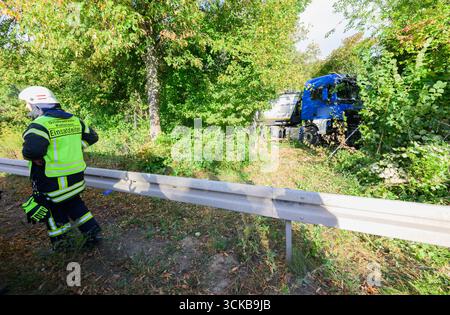 Pattensen, Deutschland. September 2025. Feuerwehrleute stehen neben einem Lkw, der an einem Unfall beteiligt war, auf der Bundesautobahn B3 im Raum Hannover. Der Lkw hatte die B3 am Morgen verlassen und die entgegenkommende Spur überquert und dabei mehrere Bäume getroffen. Quelle: Julian Stratenschulte/dpa - ACHTUNG: Firmenname wurde aus rechtlichen Gründen pixeliert/dpa/Alamy Live News Stockfoto