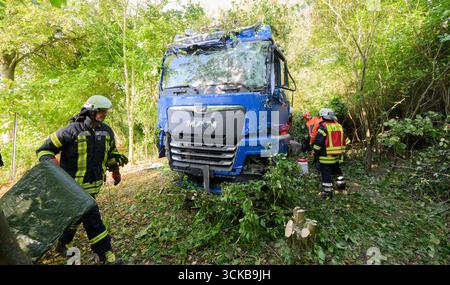 Pattensen, Deutschland. September 2025. Feuerwehrleute stehen neben einem Lkw, der an einem Unfall beteiligt war, auf der Bundesautobahn B3 im Raum Hannover. Der Lkw hatte die B3 am Morgen verlassen und die entgegenkommende Spur überquert und dabei mehrere Bäume getroffen. Quelle: Julian Stratenschulte/dpa - ACHTUNG: Firmenname wurde aus rechtlichen Gründen pixeliert/dpa/Alamy Live News Stockfoto