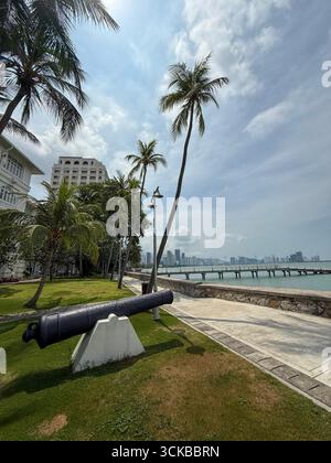 Eine Kanone in den Gärten, die auf das Meer zeigt, vor dem Eastern & Oriental (E&O) Hotel in Goerge Town, Hauptstadt Penang in Malaysia, Stockfoto