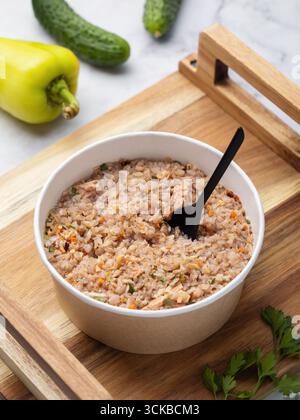 Instant-Buchweizen-Getreidebrei, der nicht mit Fleisch und Gewürzen in einem Einweg-Papierbehälter auf einem Holztablett gekocht werden muss Stockfoto