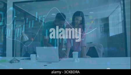 Diagramme ansehen zwei Bürofachleute, die sich im modernen Büro über ein Notebook lehnen, mit Kaffeetassen. Zusammenarbeit, Teamarbeit, Datenanalyse, modernes Design Stockfoto