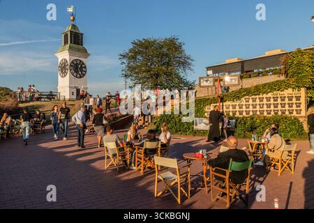NOVI SAD, SERBIEN - 3. OKTOBER 2021: Menschen in einem Café in der Festung Petrovaradin in der Nähe der Uhr, Novi Sad, Serbien Stockfoto