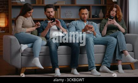 Gruppen multirassische Freunde feiern zu Hause mit Handys Gadget Süchtige Leute auf der Couch mit Smartphones chatten in sozialen Medien ignorieren jede Stockfoto