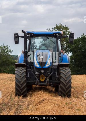 Landwirtschaft des blauen Traktors der Strohernte im abgeschnittenen Sternfeld vorne im Blick. Stockfoto