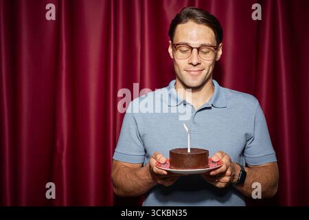 Porträt eines jungen Erwachsenen, der Geburtstagskuchen mit Kerze hält Stockfoto