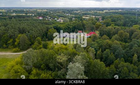 Eine Mischung aus Wäldern, Feldern und verstreuten Gebäuden in Nowy Lubiel, Polen, mit einem roten Dachhaus, einem Feldweg und einem Ackerland unter teilweise bewölktem Himmel Stockfoto