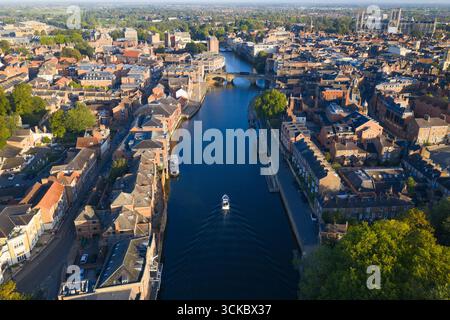 Luftbild von York, das den Fluss Ouse mit einem Boot, Clifford’s Tower, Brücken und York Minster zeigt. Stockfoto