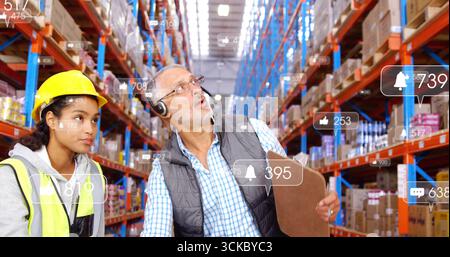 Lagermitarbeiter mit Schutzhüten und Westen, die Boxen im Gang mit Klemmbrett und Symbolen scannen. Industrie, Logistik, Effizienz, Organisation, Sicherheit Stockfoto