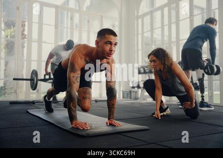 Vier sportliche Jugendliche in Sportbekleidung, die im Fitnessstudio trainieren Stockfoto
