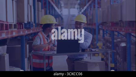 Mitarbeiter, die Helme tragen, überprüfen den Bestand auf dem Laptop am Wagen im Verteilerzentrum mit Kisten. Industrie, Logistik, Fertigung, Produktivität, Stockfoto