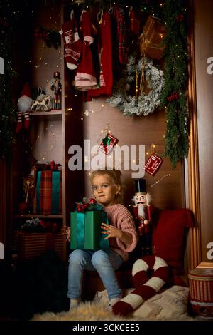 Kind mit Weihnachtsgeschenk im festlichen Abendinnenraum Stockfoto