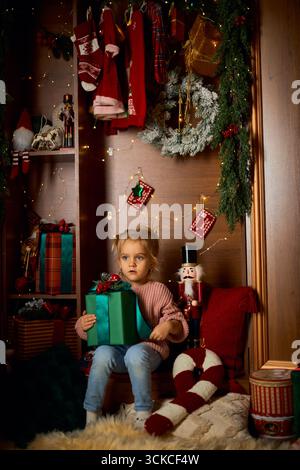 Kind mit Weihnachtsgeschenk im festlichen Abendinnenraum Stockfoto