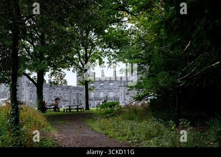 Eine wunderschöne Gartenszene mit lebhaftem Herbstlaub vor dem Hintergrund einer alten irischen Burg. Beschauliche Wanderwege laden zum Erkunden ein Stockfoto