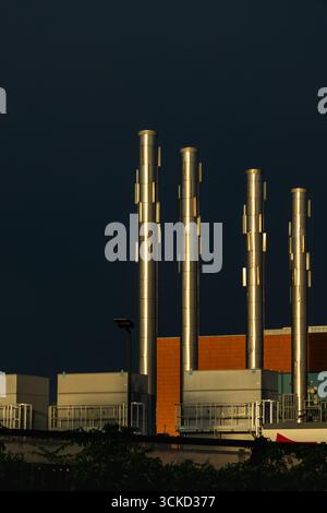 Industrieanlage mit hohen Metallschornsteinen unter dunklem Himmel Stockfoto
