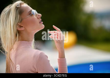 Schöne junge blonde Frau mit Sonnenbrille, die draußen posiert, Modeporträt. Lifestyle, Schönheit, Modekonzept. Stockfoto