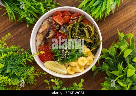 Blick von oben auf die köstliche Poke aburi saba Schüssel mit Sushi Reis, tom Yum Sauce, koreanischer Gurke, Kirschtomaten, Babymais, getrocknete Tomaten, Nikiri sa Stockfoto