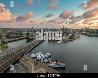 Arial Blick auf die Altstadt Stockholms, mit historischen Gebäuden, zentraler Brücke und Booten auf dem Wasser Sonnenuntergang bewölkten Himmel Stockfoto