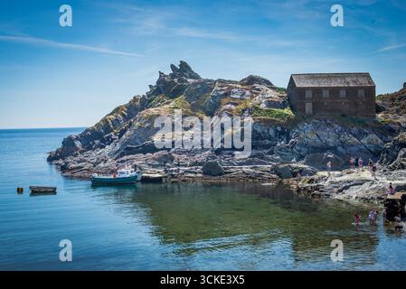 Urlauber erkunden Rocky Shoreline neben dem Old Watch House in Polperro, Cornwall, Großbritannien Stockfoto