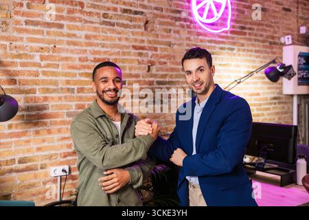 Zwei Geschäftsleute schütteln sich in modernen Büros die Hand, nachdem sie eine Einigung erzielt haben Stockfoto