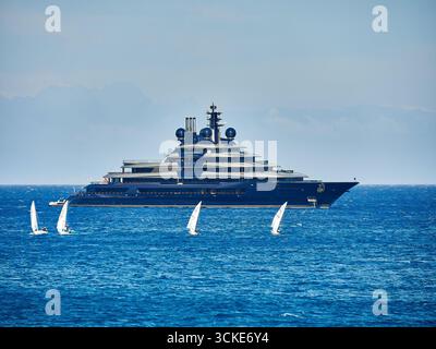 Megayacht-LUMINANZ mit kleinen Segelbooten im Vordergrund an einem klaren, sonnigen Tag Stockfoto