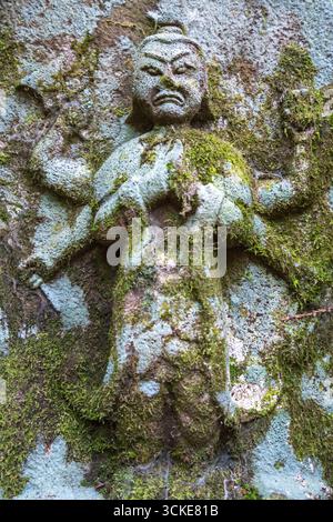 Eine moosbedeckte Myo-o-Statue aus Stein steht versteckt im Wald entlang des historischen Nakasendo-Weges zwischen Magome und Tsumago, Japan Stockfoto