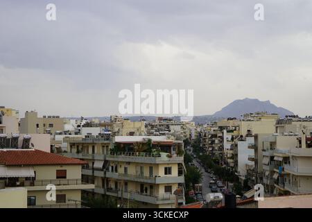 Ein erhöhter Blick auf die dichte Stadtlandschaft von Heraklion mit einem Berg an einem bewölkten Tag, der einen Einblick in das Leben der Inselstadt bietet. Stockfoto