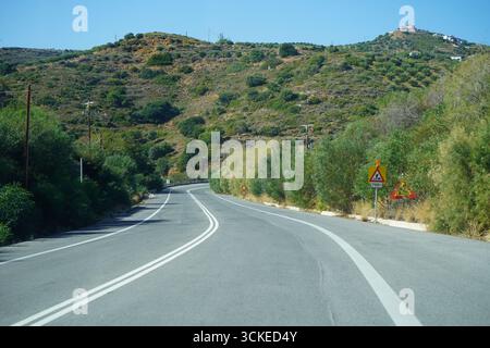 Ein malerischer Blick auf eine gewundene Asphaltstraße, die Teil der Northern Road Axis of Crete (BOAK) ist und durch die trockenen, buschbedeckten Hügel führt Stockfoto