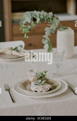 Elegante Tischeinrichtung mit Teller mit Serviette und grünem Dekor Stockfoto