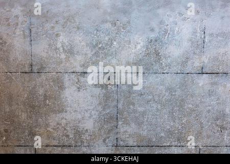 Neutrale Betonstruktur mit abgenutzter Patina, feinem Aggregat und subtilen Rasternähten zwischen den Platten. Vielseitiger Hintergrund für Architektur, Design-Mocku Stockfoto