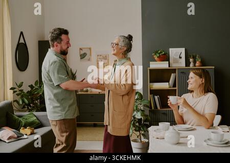Ein Mann im mittleren Alter, der Hände hält und eine ältere kaukasische Frau lächelt Stockfoto