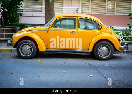 Gelber Retro-VW-Käfer, klassischer VW-Käfer auf einer Stadtstraße, Oldtimer mit modernem Twist Stockfoto