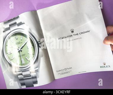 Paris, Frankreich - 2. September 2025: Paris, Frankreich - 2. September 2025: Eine Hand hält ein Magazin offen, das eine Rolex Oyster Perpetual Uhren-Werbung mit gre zeigt Stockfoto