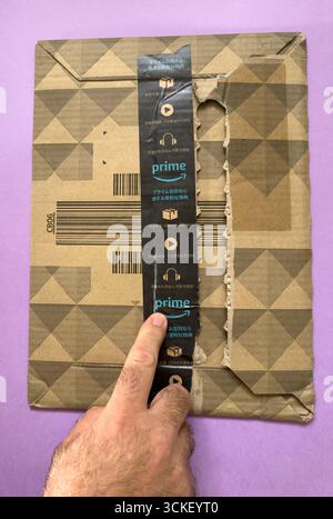 Paris, Frankreich - 2. September 2025: Kartonverpackung mit Amazon Prime Klebeband teilweise geöffnet und Hand auf die Oberfläche zeigt E-Commerce-Lieferung und Sch Stockfoto