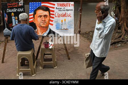 Mumbai, Indien. September 2025. Ein Lehrer der Kunstschule Gurukul malt ein Poster, das dem US-politischen Aktivisten und Autor Charlie Kirk Tribut zollt, während ein Mann, der auf seinem Handy spricht, vor der Kunstschule vorbeiläuft. Die Gurukul School of Art zollt dem 31-jährigen Charlie Kirk Tribut, einem politischen Aktivisten, Autor und engen Verbündeten von Präsident Donald Trump, der erschossen wurde, als er bei einer Veranstaltung an der Universität Utah Valley mit einer großen Menge sprach. Quelle: SOPA Images Limited/Alamy Live News Stockfoto