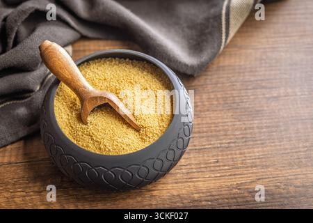 Ungekochter Couscous in einer Schüssel auf einem Holztisch. Stockfoto