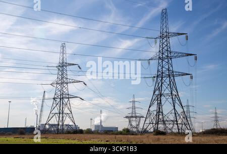 Eine Sammlung von Strommasten vor einer Industrieszene Stockfoto