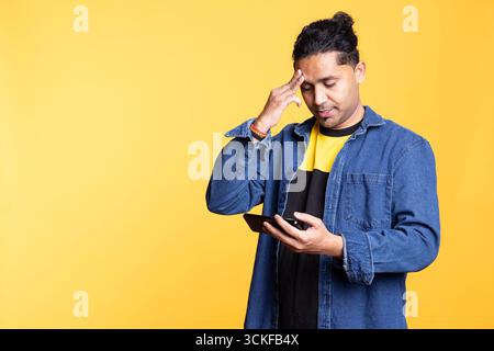 Verärgerte, unzufriedene Person, die sich frustriert fühlt und Controller im Studio hält, Videospiele verliert und etwas missbilligt. Enttäuschter indianer, enttäuscht vom verlorenen Gameplay. Stockfoto