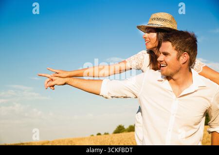 Fröhlicher junger Mann mit seiner blonden Freundin in der Natur Stockfoto