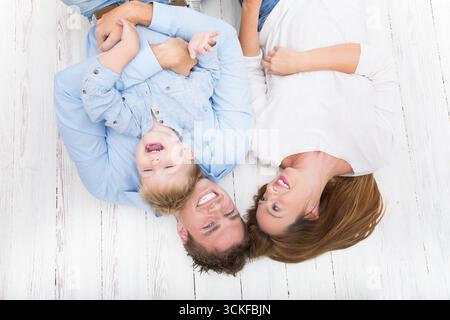 Eltern mit einem Jungen, der auf dem Holzboden liegt, Blick von oben Stockfoto