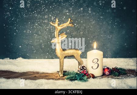 Weihnachtsdekoration mit brennender Kerze und goldener Rentierfigur, 3. Adventszeit Stockfoto
