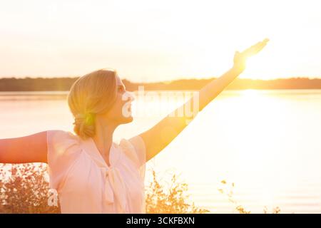 Eine junge Frau gegen das Licht, die eine Meditationsübung macht Stockfoto
