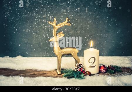 Weihnachtsdekoration mit brennender Kerze und goldener Rentierfigur, 2. Adventszeit Stockfoto
