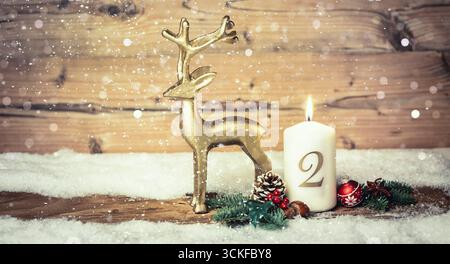 Weihnachtsdekoration mit brennender Kerze und goldener Rentierfigur, 2. Adventszeit Stockfoto