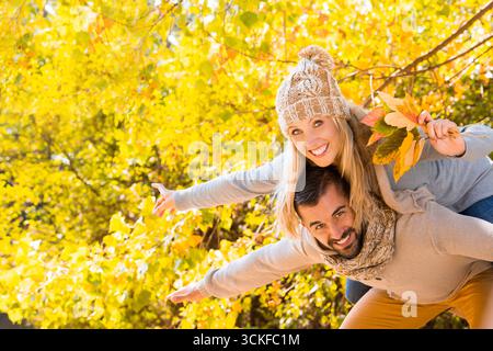 Fröhlicher junger Mann mit seiner blonden Freundin im Wald Stockfoto