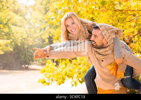 Fröhlicher junger Mann mit seiner blonden Freundin im Wald Stockfoto