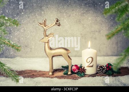 Weihnachtsdekoration mit brennender Kerze und goldener Rentierfigur, 2. Adventszeit Stockfoto