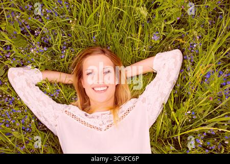 Eine junge Frau, die zufrieden auf einer Wiese liegt Stockfoto