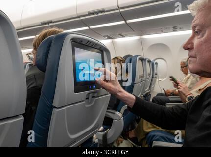 Männlicher Senior-Passagier, der auf dem Sitz sitzt, Entertainment-Bildschirm, Delta Airlines, 2025, USA Stockfoto