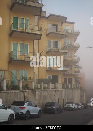 Appartementhäuser mit Balkonen und geparkten Autos im Morgennebel in Enna Sizilien, Italien, mit Blick auf die Stadt Stockfoto