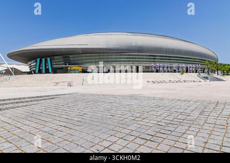 Ein breiter Blick vom Boden auf das Äußere der MEO Arena, betont seine beeindruckende Größe und einzigartige elliptische Form mit einer geräumigen Kopfsteinpflasterführung Stockfoto